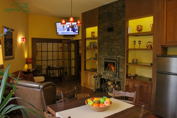 A cozy living room with a fireplace, wooden furniture, and a television mounted on the wall.