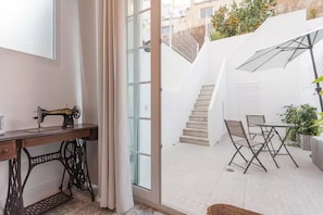 Um quarto com uma máquina de costura, uma mesa com cadeiras, uma escada e vista para o exterior.