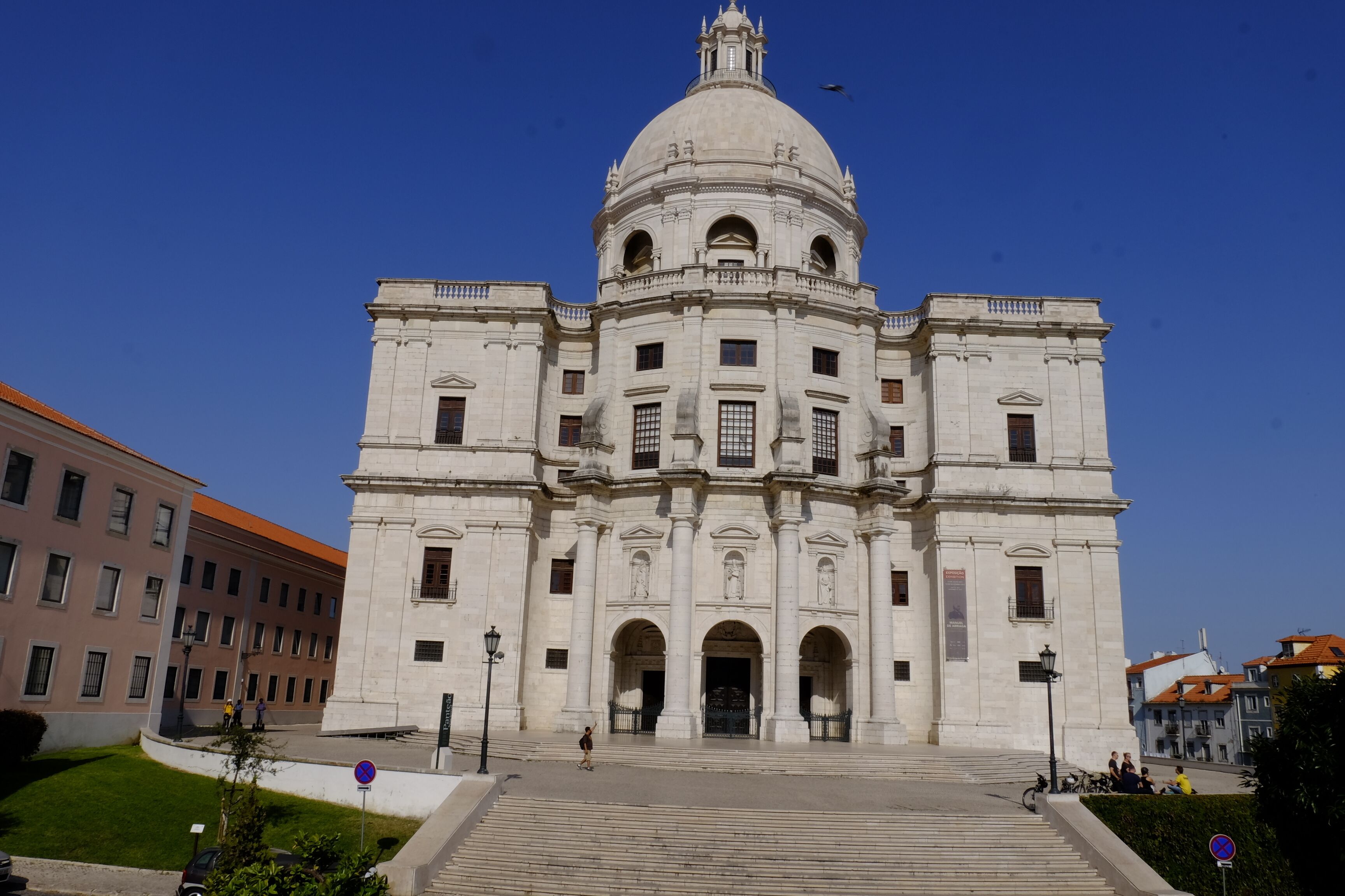 A large, historic building with a central dome and symmetrical facade, featuring multiple arches and columns.