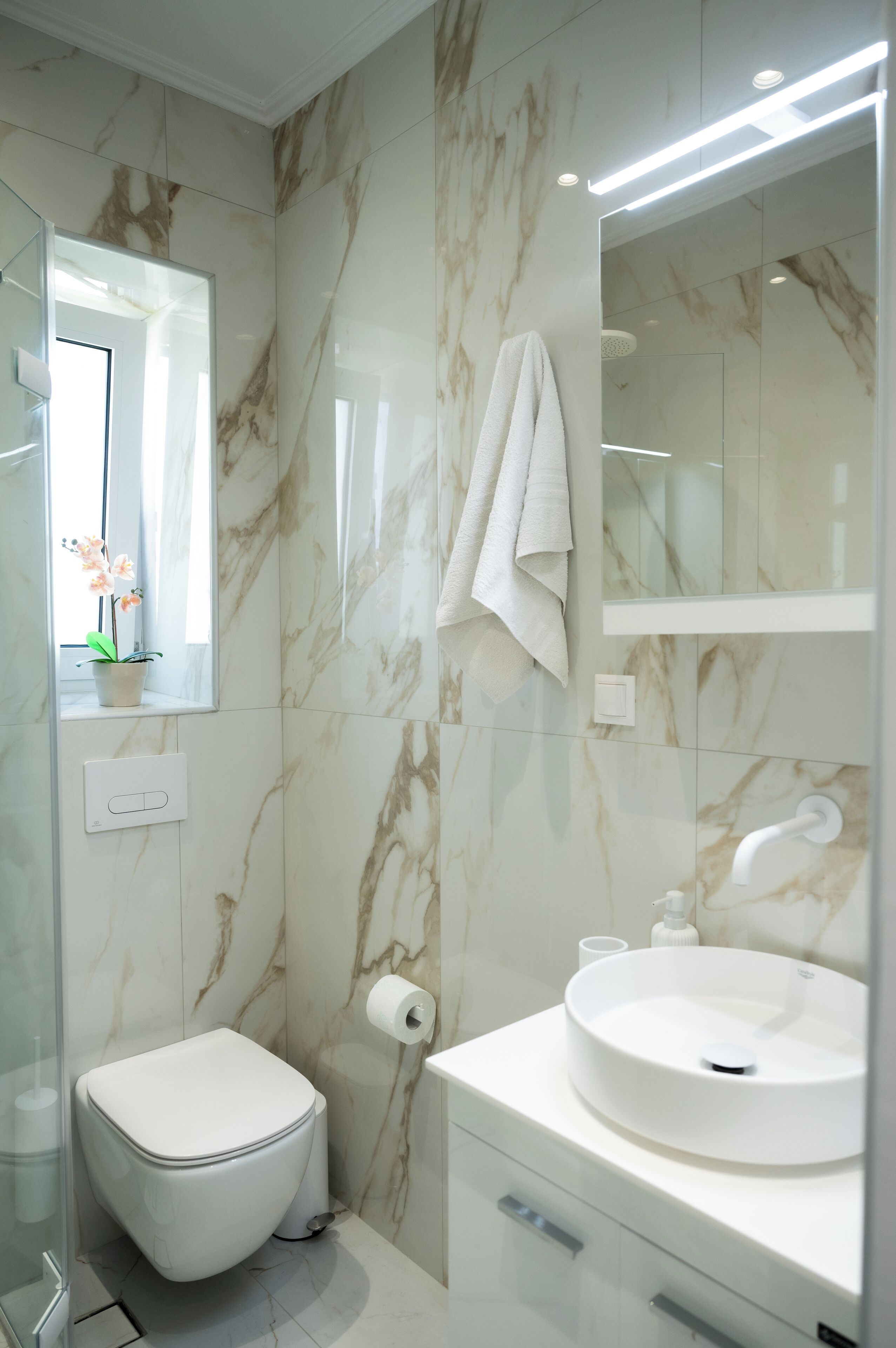 Ein modernes Badezimmer mit Toilette, Waschbecken und Spiegel.