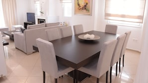 A modern dining area with a dark wooden table, light grey upholstered chairs, and a white vase with spherical objects on the table.