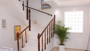 A staircase with wooden railings, a potted plant, and a window with blinds.