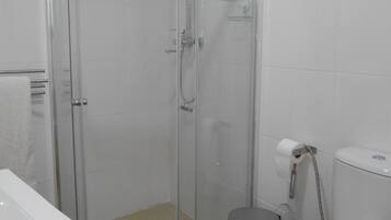 A bathroom with a glass-enclosed shower, a toilet, and a sink.