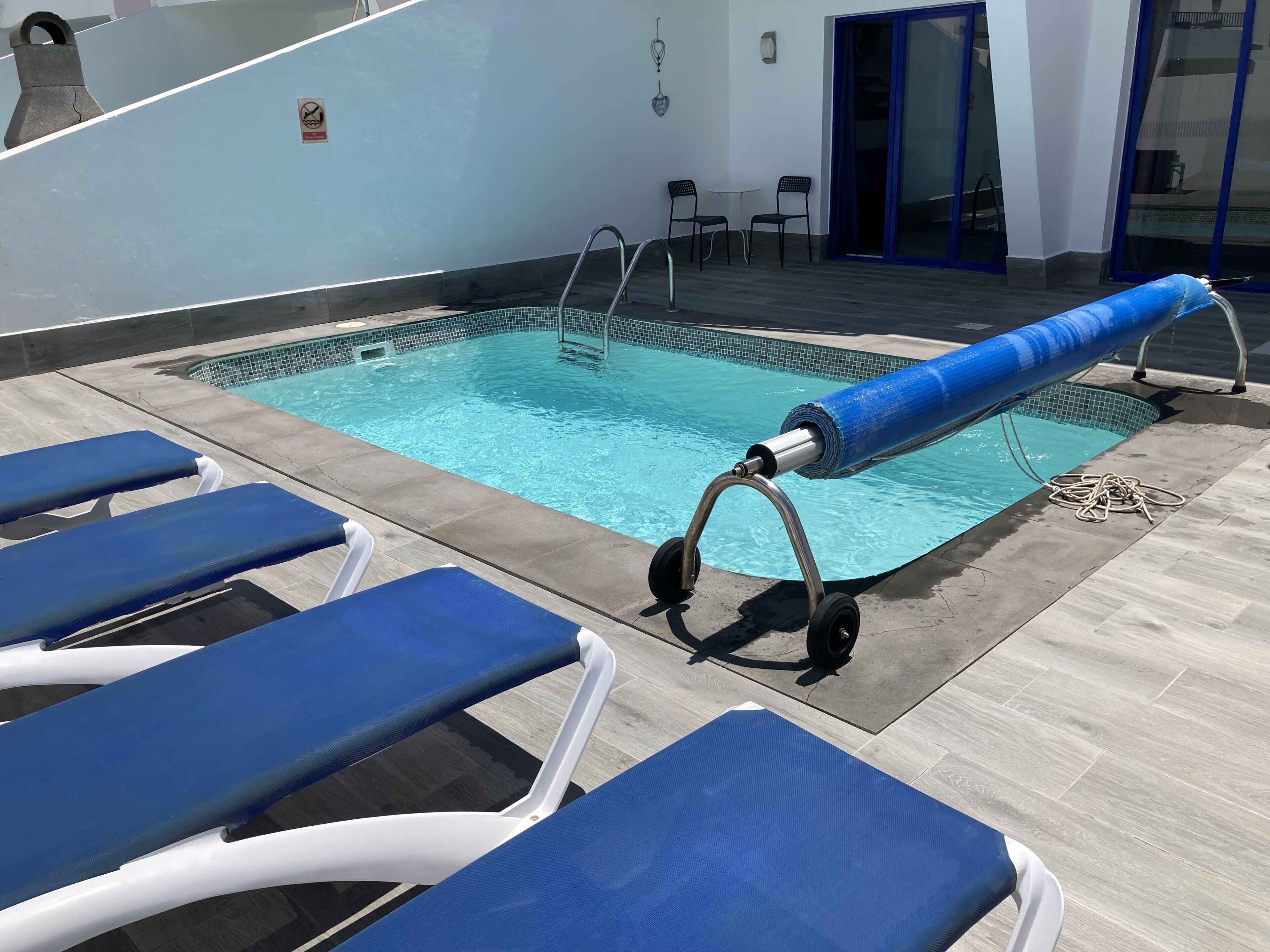Ein Poolbereich mit blauen Liegestühlen und einem Liegestuhl am Pool.