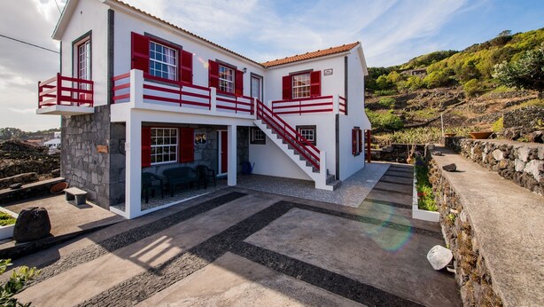 Ein zweigeschossiges Haus mit rotem und weißem Anstrich, einer Steinfassade und einer Treppe, die zum Obergeschoss führt.