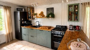 A kitchen with a wooden countertop, a stove, a refrigerator, and a microwave. - Hjartarstaðir Private Country Retreat with Hot Tub (Hella)