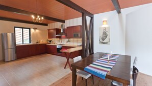 Eine moderne Küche mit Holzschränken, einem Edelstahlkühlschrank und einem Essbereich mit Holztisch und Stühlen.
