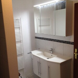 Un baño con un lavabo blanco, un espejo encima y un perchero para toallas.