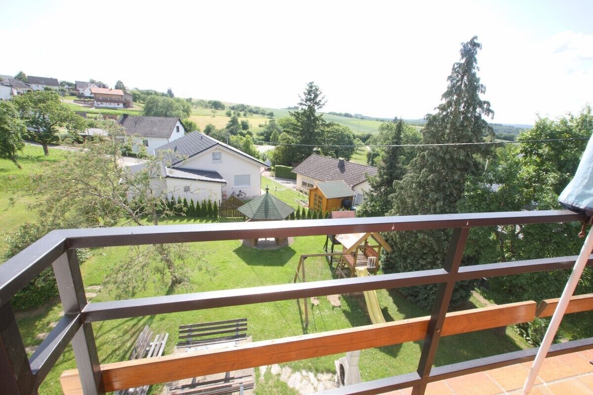 A balcony with a view of a residential area, including houses and a park.