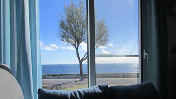 A room with a large window overlooking a tree and a body of water.