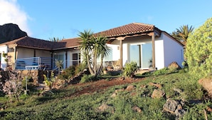 A two-story house with a tiled roof, a balcony, and a garden with rocks and plants. - La Hoya, cozy, quiet country house   (alajero)