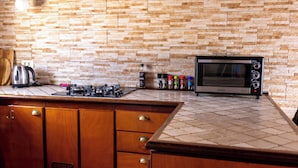 A kitchen with a stone backsplash, a microwave, and various kitchen appliances. - La Hoya, cozy, quiet country house   (alajero)
