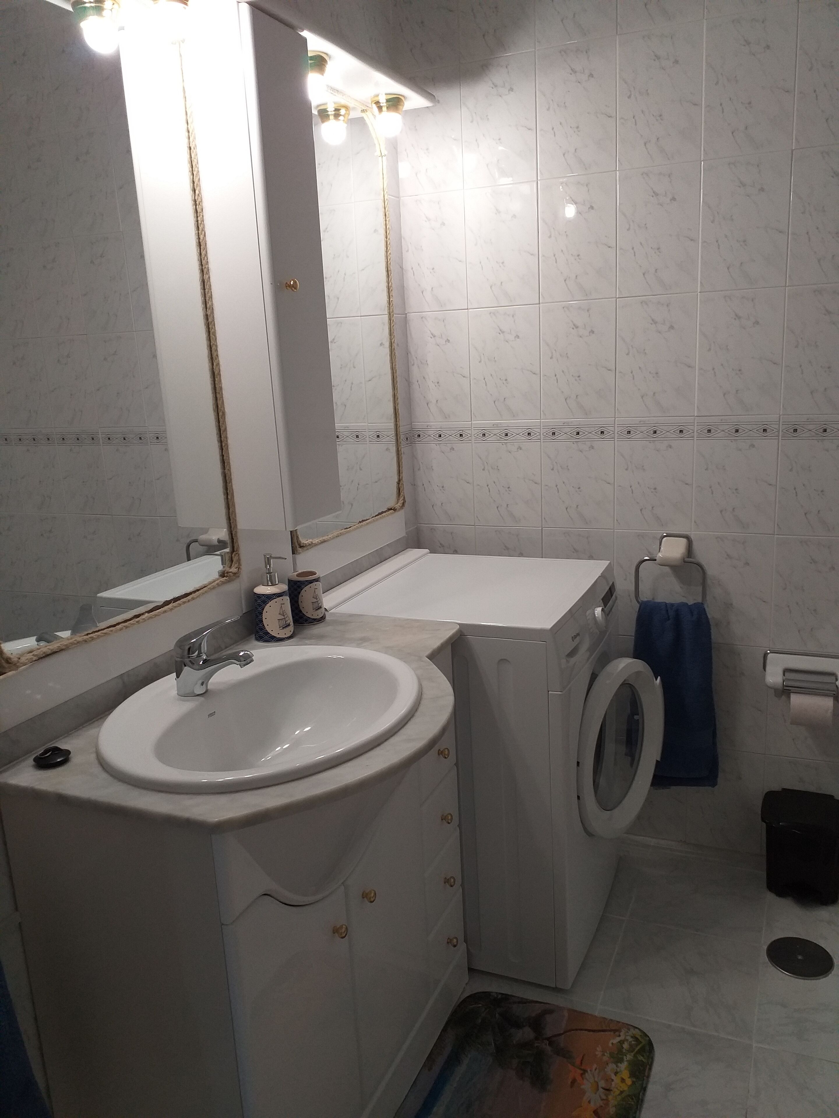 Une salle de bain équipée d’un lavabo, d’un miroir, d’un lave-linge et de toilettes.