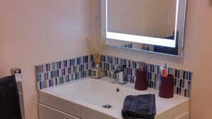 Une salle de bain avec un lavabo blanc, un miroir, des toilettes et un tapis à rayures.