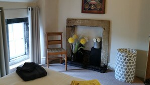 Une chambre d’hôtel avec un lit, une chaise, une cheminée et une fenêtre.