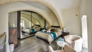 Un dormitorio con un espejo arqueado grande, dos camas, una mesa redonda pequeña y una silla.