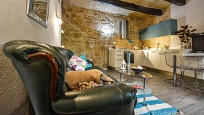 Una sala de estar acogedora con un sofá de cuero, una mesa de centro de vidrio y una pared de piedra.