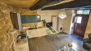Eine kompakte Küche mit Steinwand, einer Kandelaber und einer Waschmaschine, sowie ein Essbereich mit Tisch und Stühlen.