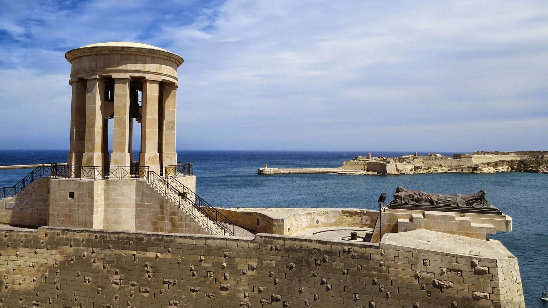 Une fortification côtière dotée d’une tour centrale, d’un escalier menant à la tour et d’une statue située à droite.