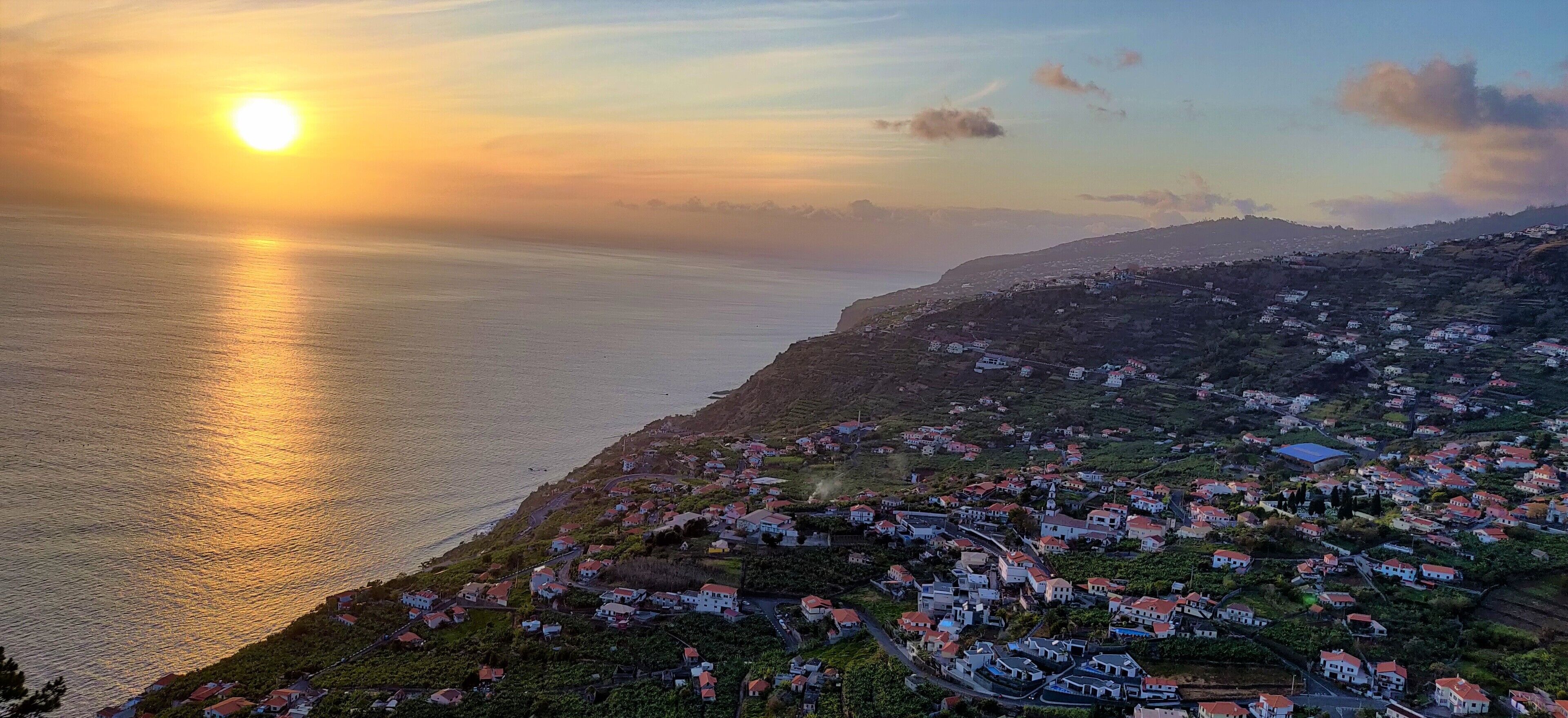 Un village côtier avec des maisons construites sur le flanc de la colline, offrant une vue sur la mer.