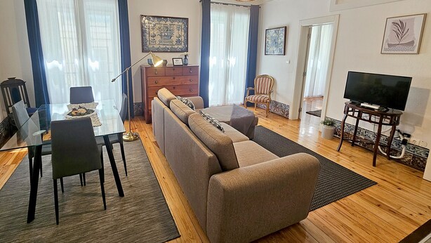 A modern living room with a sofa, dining table, chairs, and a television. - Cozy Palace in Lisbon for 2 to 6 people (Lisboa)