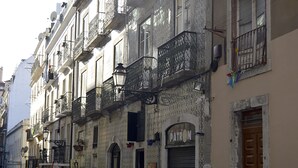 A row of historic buildings with ornate balconies and a closed shutter on the ground floor. - Cozy Palace in Lisbon for 2 to 6 people (Lisboa)