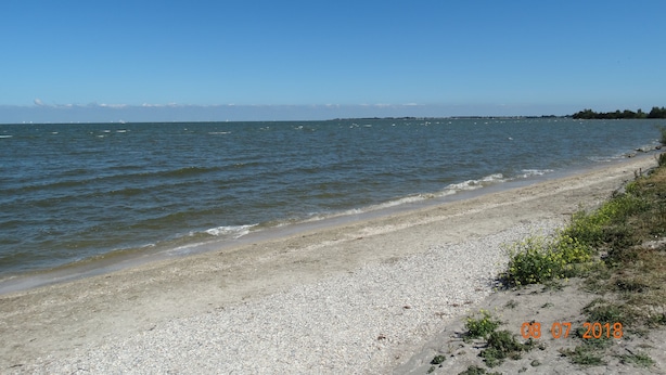 Een strand met een kiezelstrand en rustig water.
