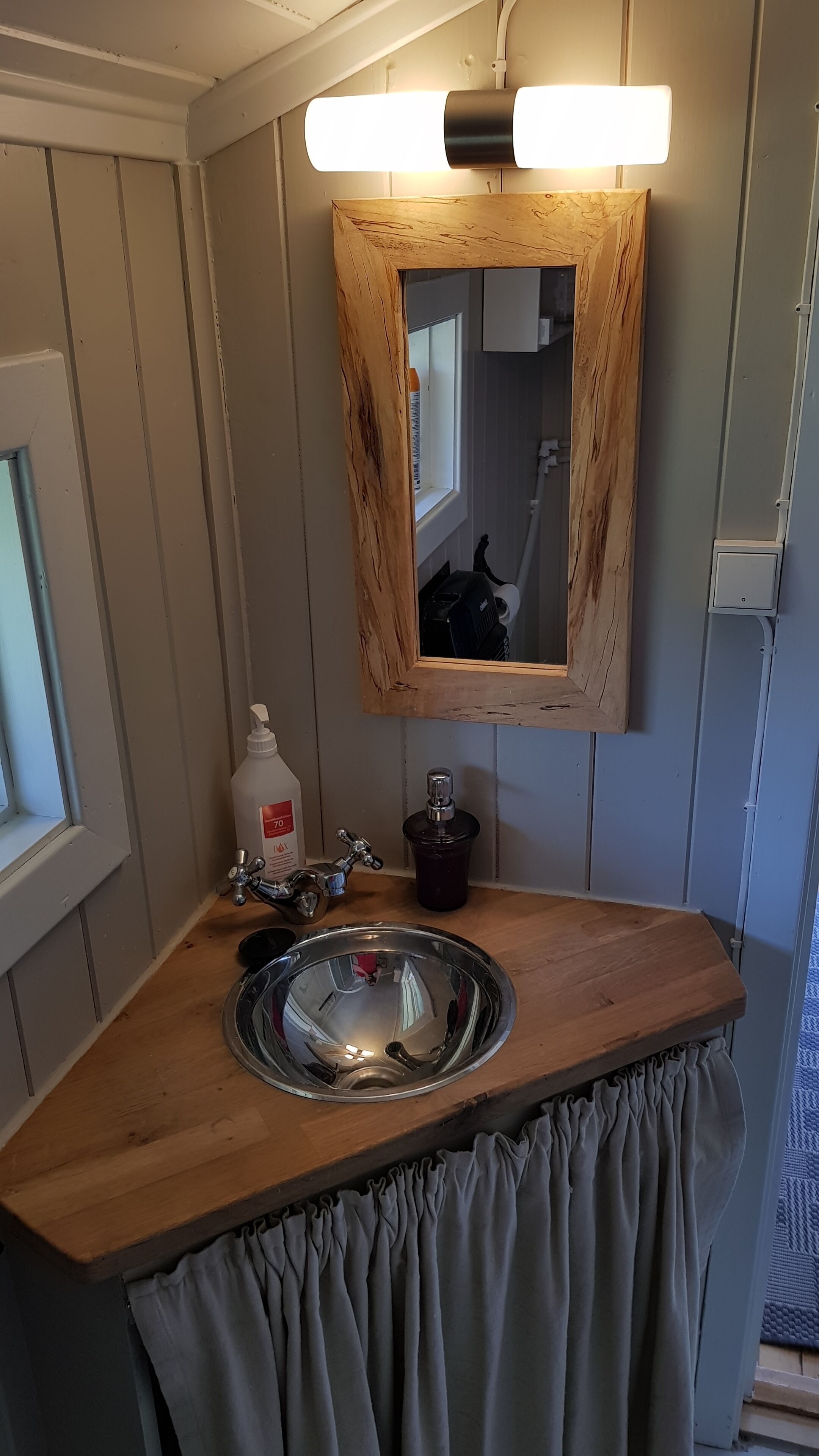 A bathroom with a wooden vanity, a mirror, a sink, and a window.