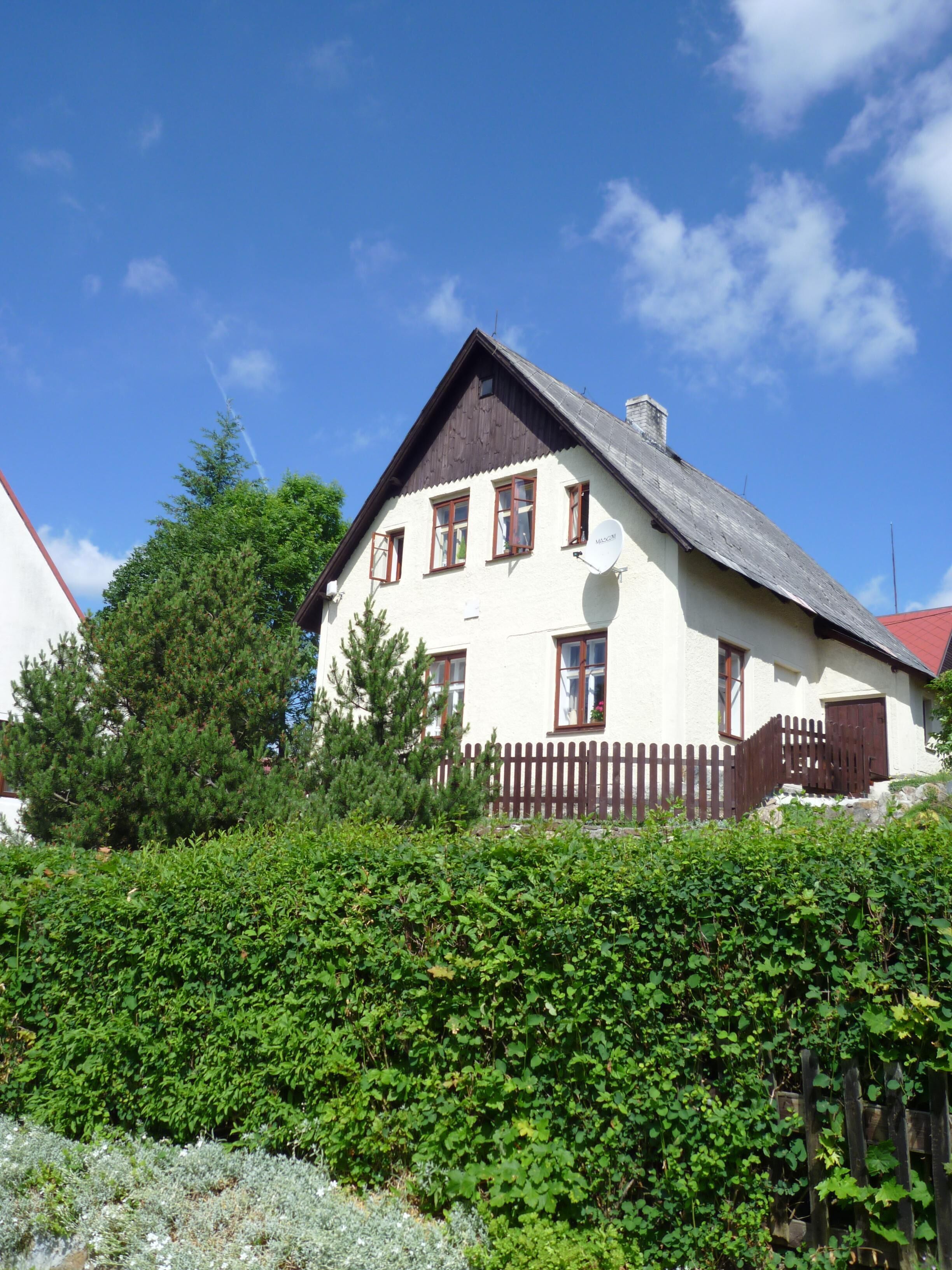 A white building with a brown roof and a wooden fence.