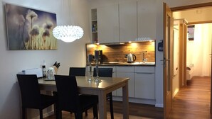 A modern kitchen with wooden cabinets, a dining table with chairs, and a pendant light. - Romantic apartment with fantastic views, WiFi free (Winterberg)