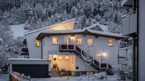 A two-story building with a staircase leading to the upper floor, surrounded by snow-covered trees.