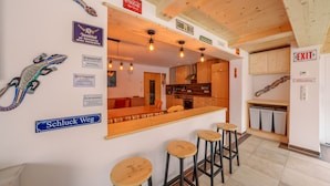 A modern kitchen with wooden cabinets, a bar area with stools, and a sign indicating an exit. - Holiday apartment for up to 8 people! No dogs! (Tux)