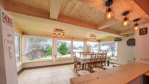 A dining area with a wooden table and chairs, large windows with curtains, and a view of the outdoors. - Holiday apartment for up to 8 people! No dogs! (Tux)