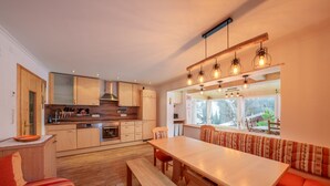 A modern kitchen with wooden cabinets, a dining area with a bench, and a large window providing natural light. - Holiday apartment for up to 8 people! No dogs! (Tux)