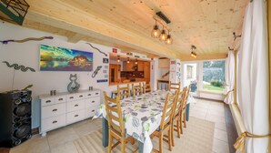 A dining area with a long table, wooden chairs, a white cabinet, and a painting on the wall. - Holiday apartment for up to 8 people! No dogs! (Tux)