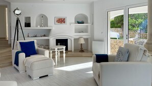 Un salón espacioso con sofás blancos, una chimenea y vistas al exterior.