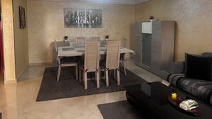 Un coin repas avec une table et des chaises, un canapé, un meuble et un tableau au mur.