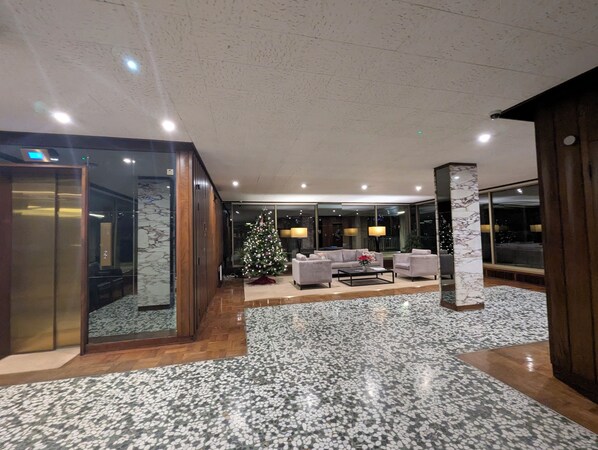 Un hall d’entrée spacieux avec un sol en marbre, un sapin de Noël et un coin salon comprenant des canapés et une table basse.