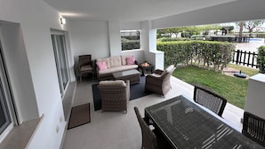 A covered patio area with wicker furniture, a sofa, and a dining table.