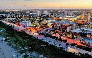A coastal cityscape with a beachfront hotel, multiple high-rise buildings, and a busy street.