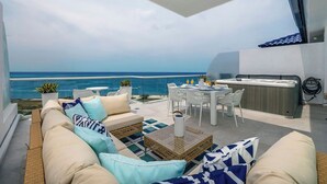 A modern outdoor living area with a sofa, dining table, and chairs, overlooking a body of water. - Heaven can wait,I found a paradise with Ocean view (Noord)