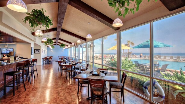 A spacious dining area with large windows offering a view of the ocean and beach umbrellas. - Ocean Views | Pool | 8th Floor 1BR | Sleeps 6 | Free Daily Activities (Daytona Beach)