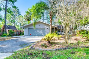 Set amidst lush trees, this single-story house offers a serene retreat with a garage and driveway.