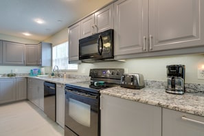 Prepare meals in a functional kitchen with stainless steel appliances, granite countertops, and ample counter space.