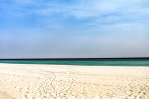 Ein sandiger Strand mit Fußspuren, die ins Wasser führen.