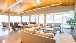 Un espacio interior amplio con techo alto, ventanas grandes y una variedad de asientos, incluyendo sofás y sillones.