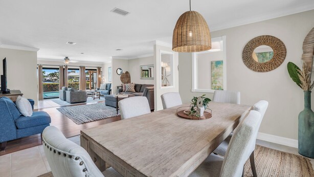 Een ruime woonkamer met een houten eettafel, zachte zitplaatsen en een groot raam met uitzicht op de omgeving.