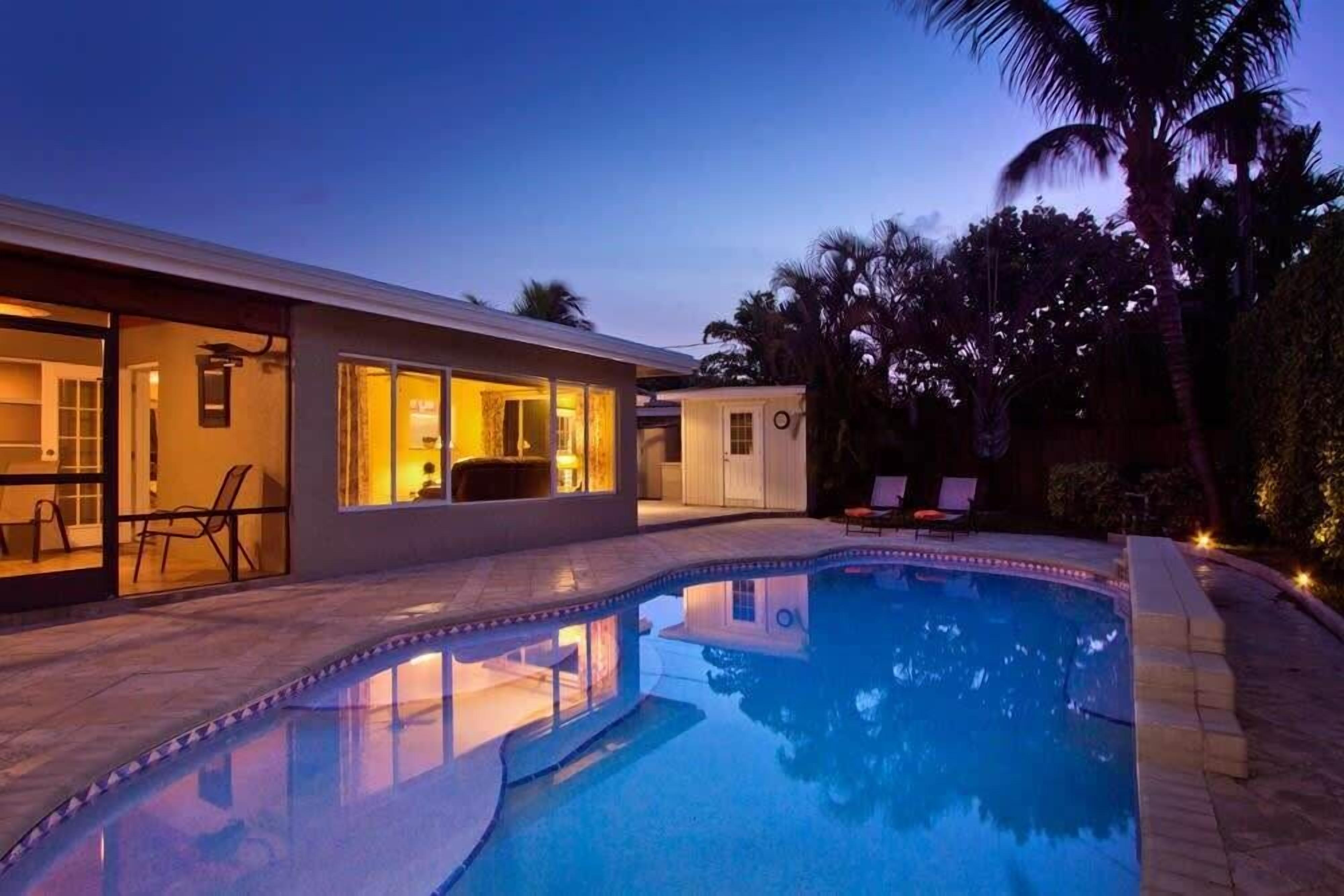 Une maison moderne dotée d’une piscine, d’un espace extérieur aménagé et d’une entrée bien éclairée.