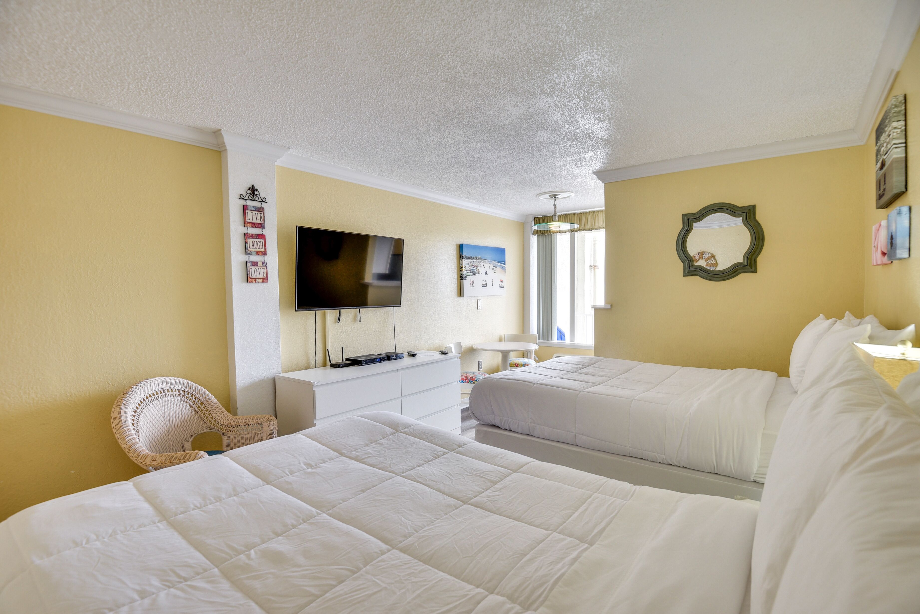 A hotel room with two beds, a television, a desk, and a chair.
