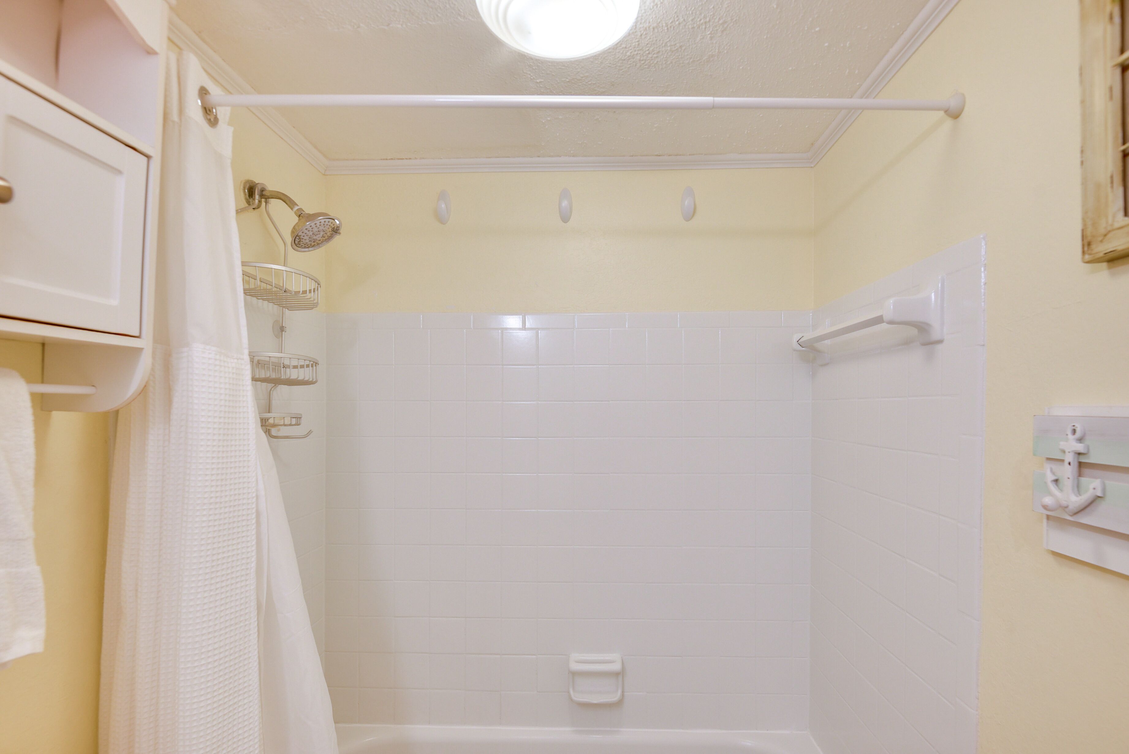 Un baño con ducha, toallero y bañera blanca.